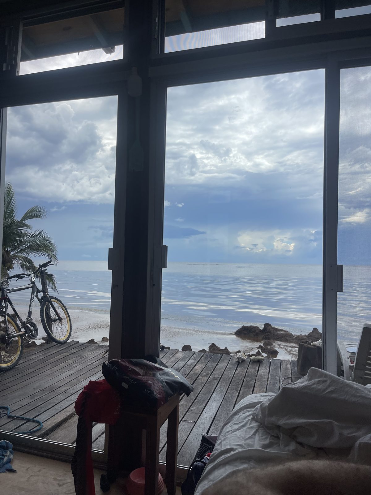 Open glass doors looking out onto the deck, a bicycle parked outside, a quiet sea beyond.